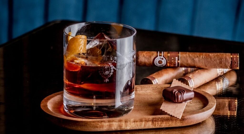 tumbler with liquid next to cigar on table