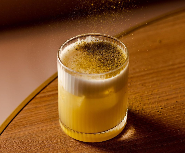 Yellow tequila cocktail on wooden table with yellow dust 